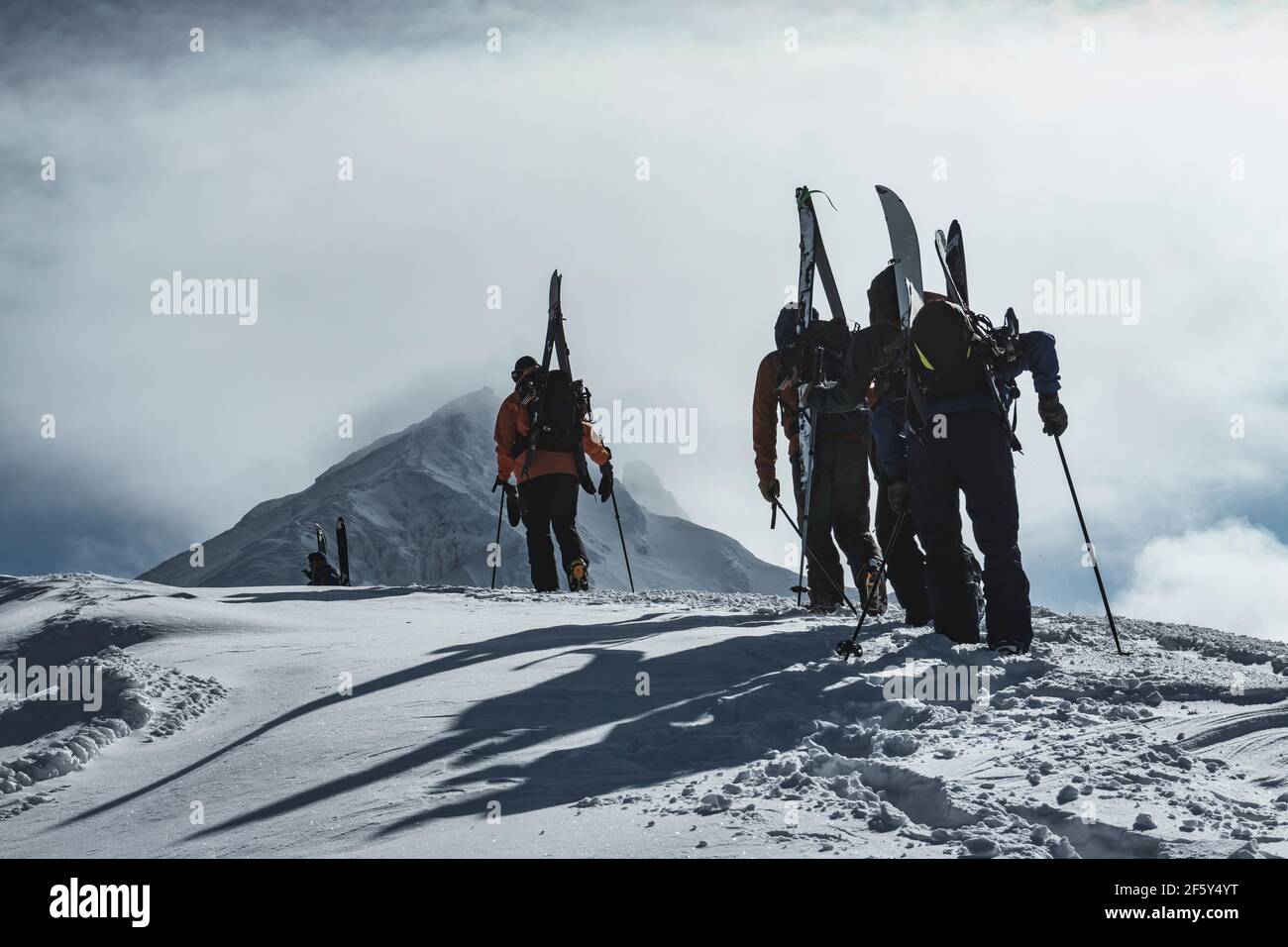 Rückansicht von Menschen mit Rucksäcken und Splitboards auf Snowcapped Berg gegen bewölkten Himmel Stockfoto