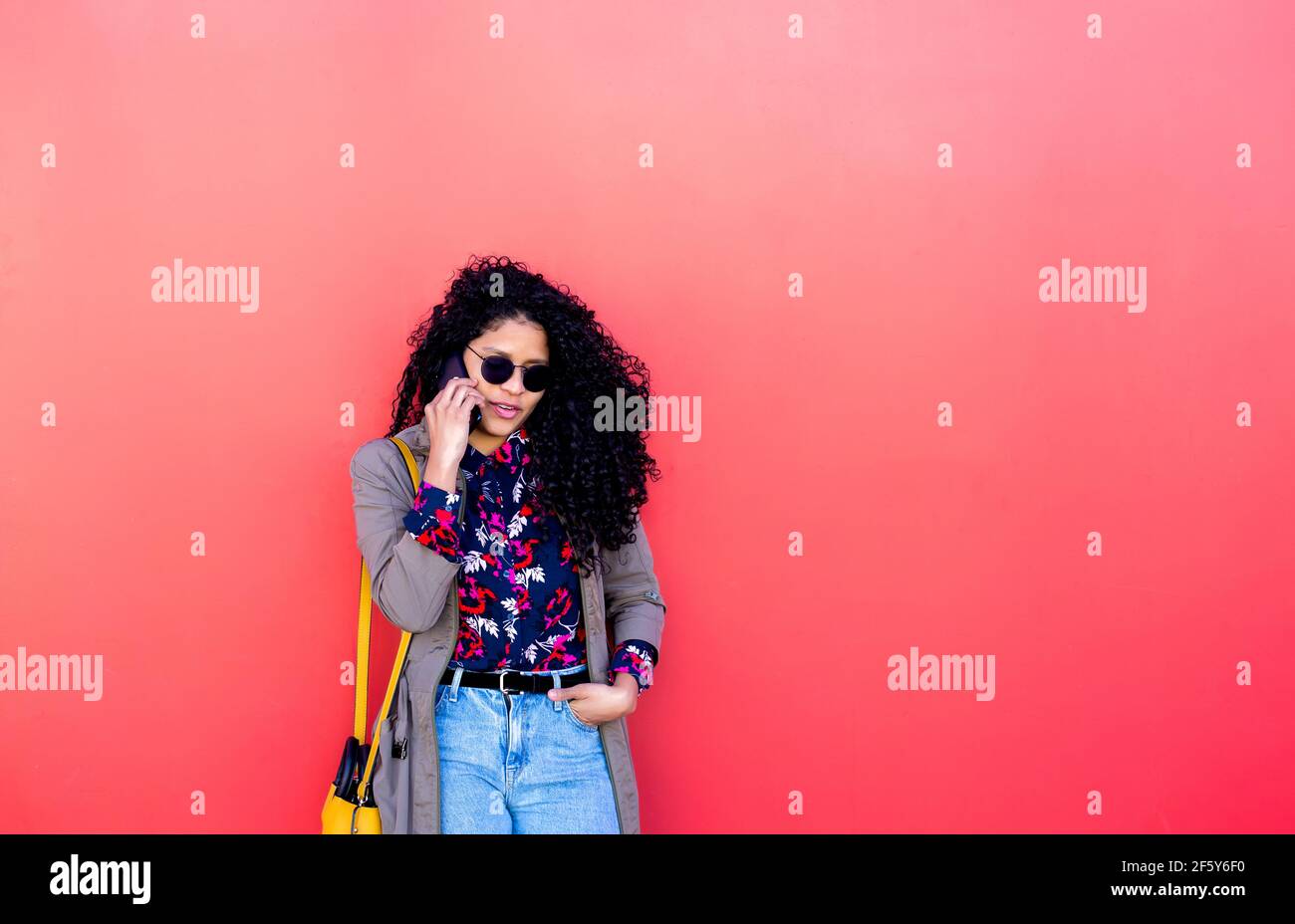 Glückliche afroamerikanische junge Frau im Gespräch mit Handy in der Stadt Stockfoto