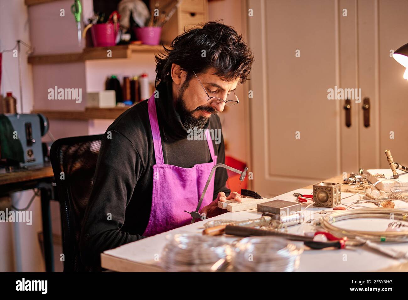 Juwelier Handwerker schneiden eine Metallplatte mit einer Säge an Der Arbeitstisch in der Werkstatt Stockfoto