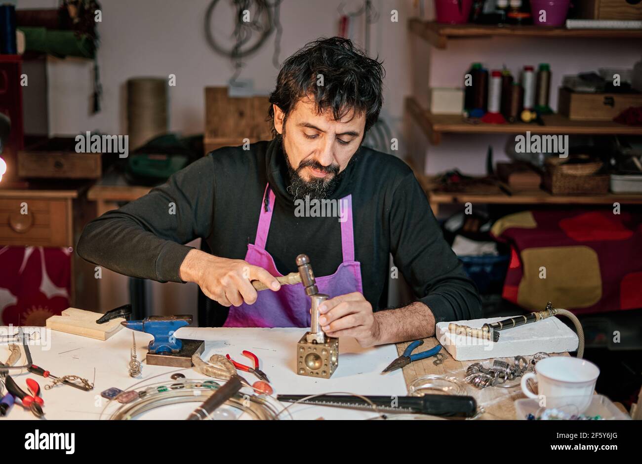 Juwelier Handwerker schlagen eine Metallplatte mit dem Hammer auf Der Arbeitstisch in der Werkstatt Stockfoto
