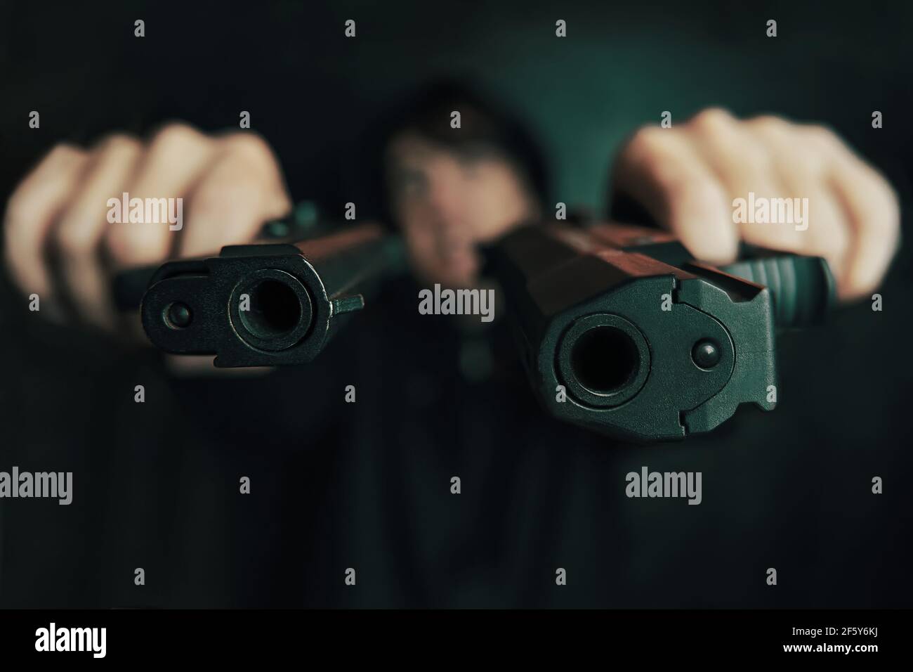 Nahaufnahme von zwei Geschützmuzzles. Guy droht mit Schusswaffe. Zwei Pistolen in Menschenhand sind auf die Kamera gerichtet. Verbrecher mit Waffe. Stockfoto