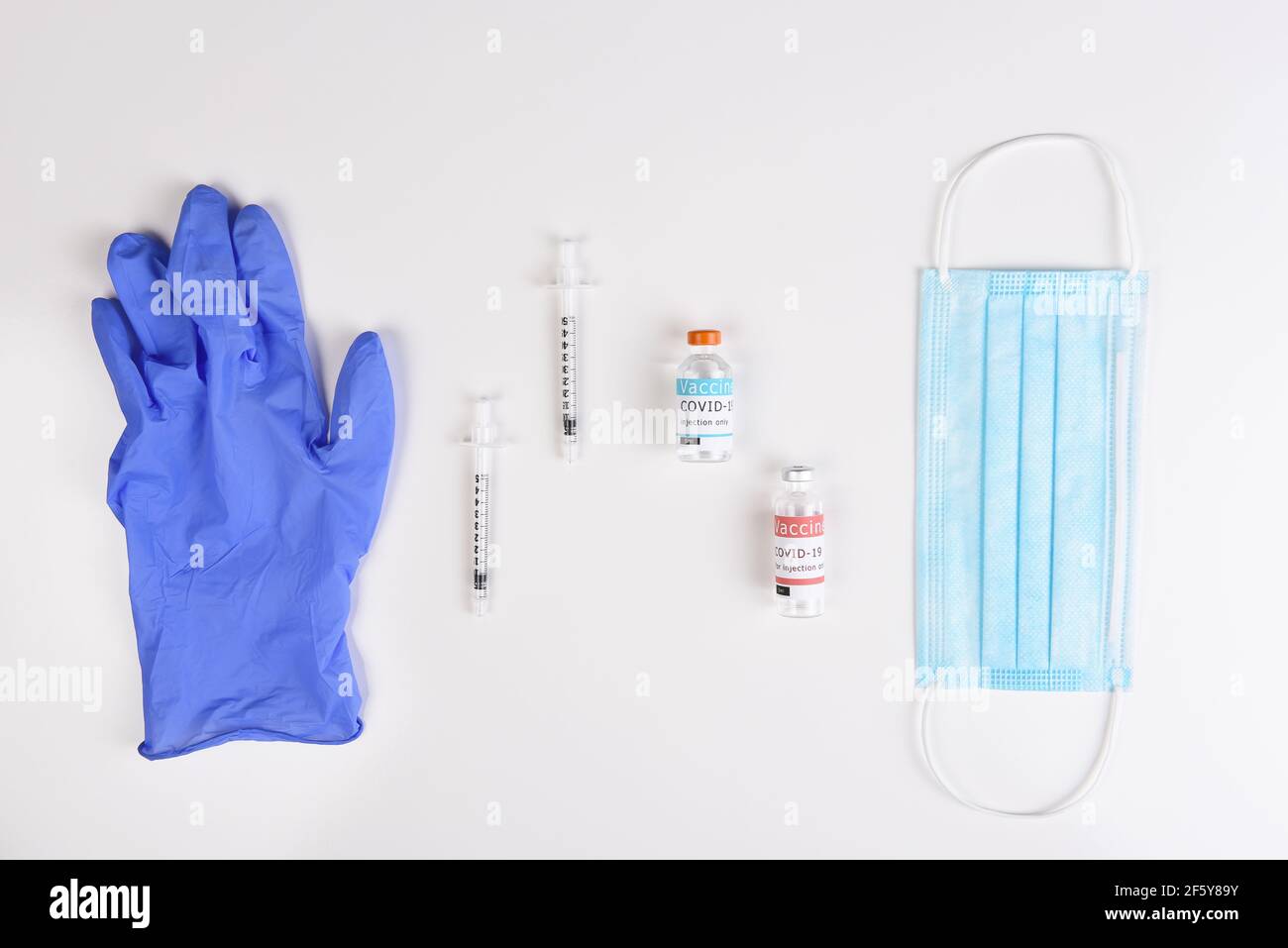 Ausrüstung zur Verabreichung einer Covid19-Impfung. Flach legen mit OP-Maske, Spritzen, Impfstofffläschchen und Handschuh. Stockfoto