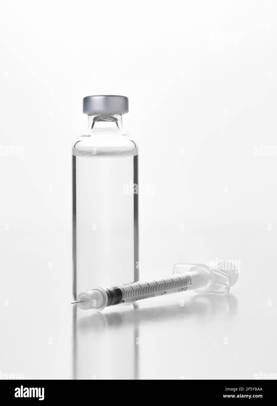 Nahaufnahme eines Fläschchens eines injizierbaren Medikaments oder Impfstoffs und Spritze auf Weiß. Flasche hat kein Etikett. Stockfoto