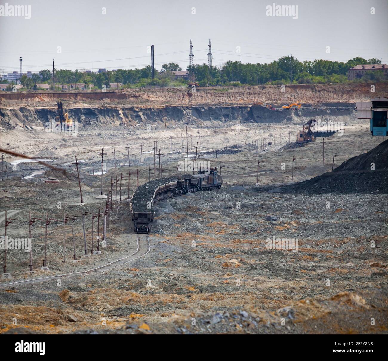 Rudny/Kasachstan - Mai 14 2012: Tagebau von Eisenerz. Eisenbahnzug und Diesellokomotive im Steinbruch, der Erz zur Konzentrieranlage transportiert. Stockfoto