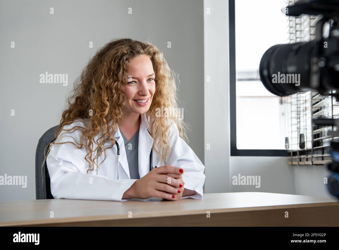 Lächelnd fröhlich kaukasischen Frau Arzt Blick auf die Kamera, während Live-Streaming aus dem Krankenhaus Stockfoto
