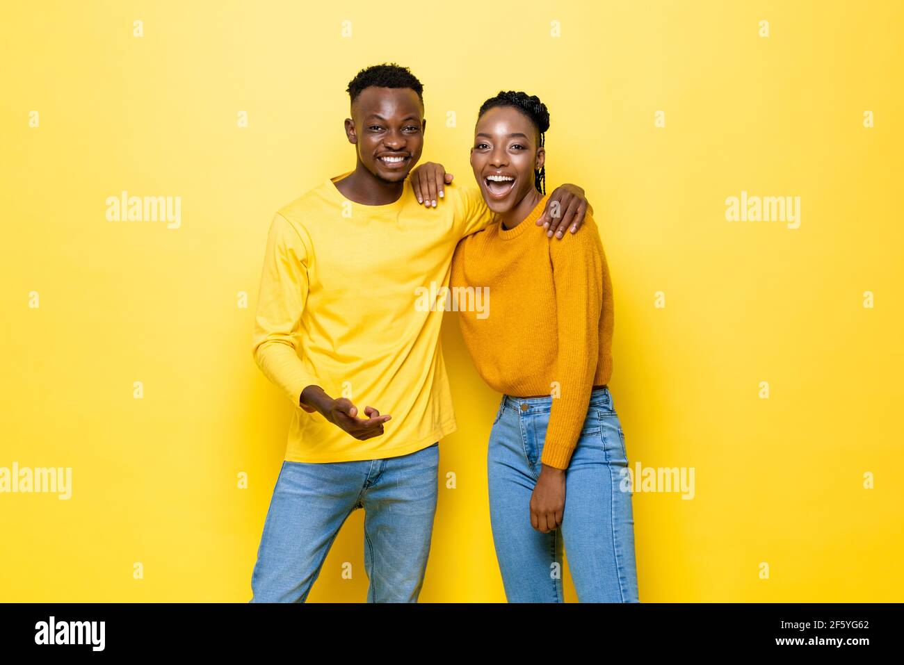 Glücklich lächelndes junges afroamerikanisches Paar in gelbem isoliertem Studio Hintergrund Stockfoto