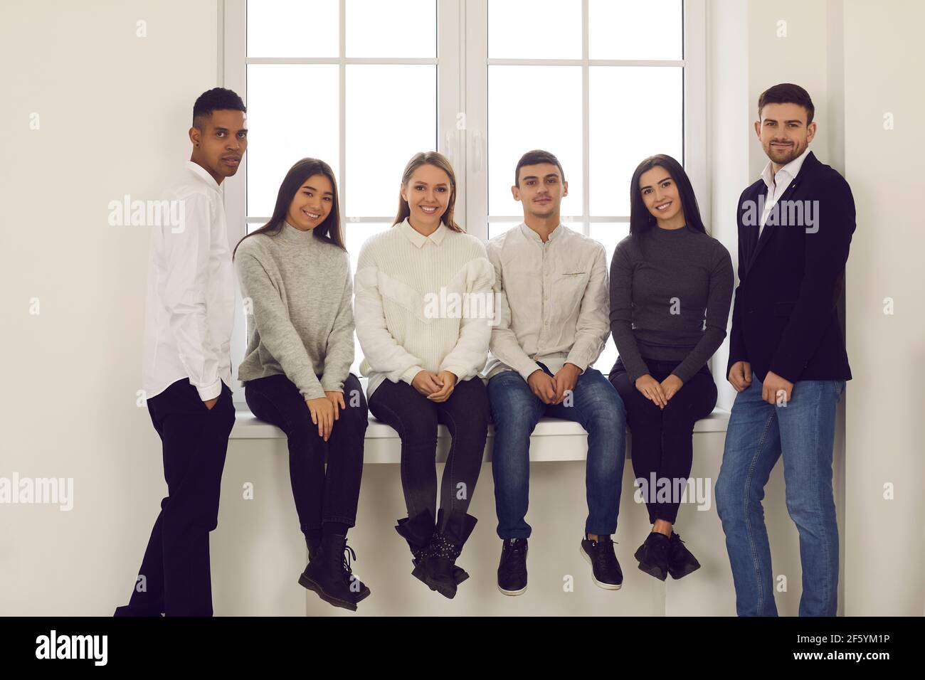 Glückliche junge multiethnische Studenten, Freunde oder Kollegen lächeln und schauen in die Kamera Stockfoto