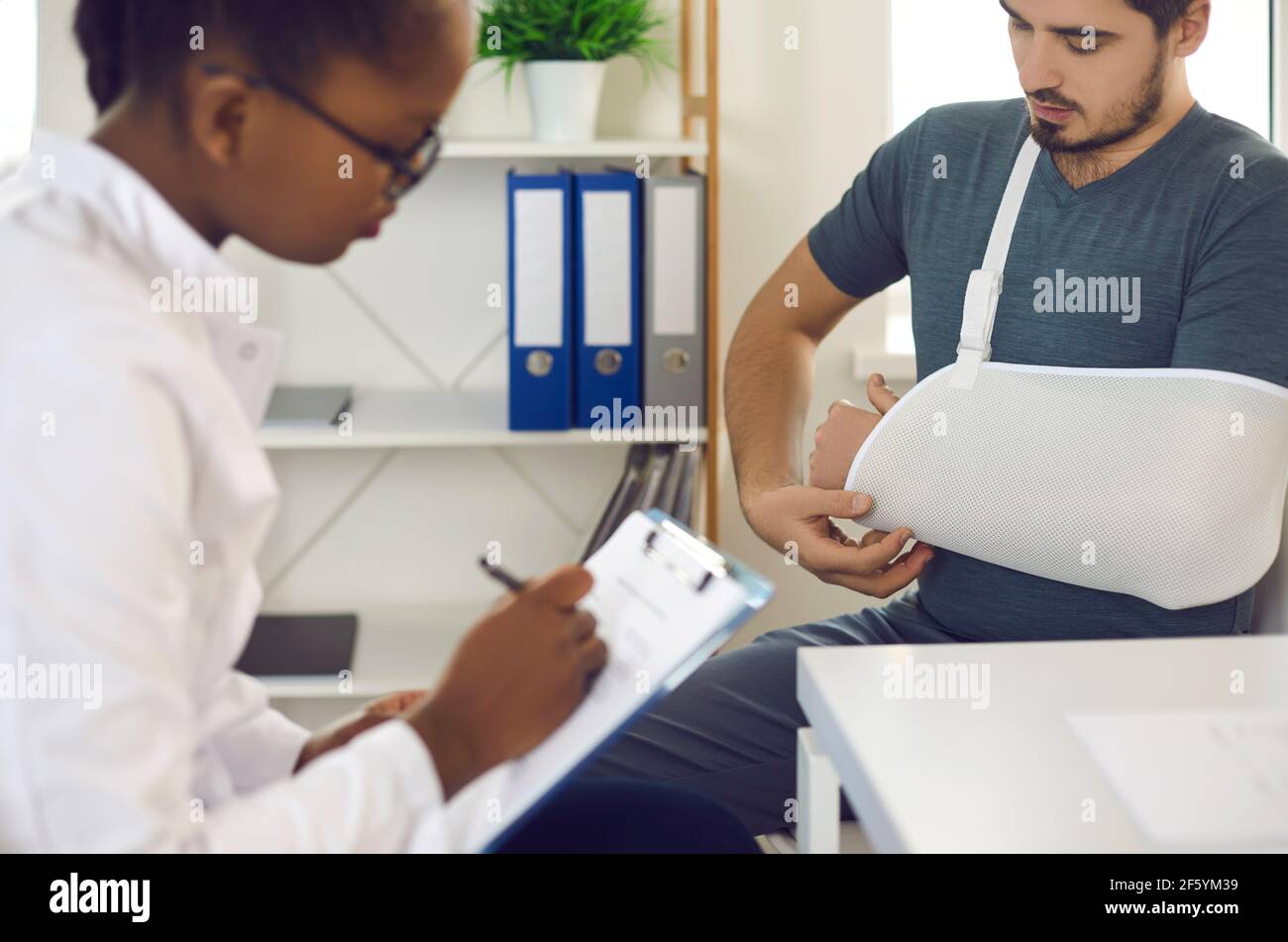 Junger Mann mit gebrochener Hand oder Arm in Schlinge Wegfahrsperre Zum Arzt im Krankenhaus Stockfoto Junger Mann mit gebrochener Hand oder Arm in Schlinge Wegfahrsperre Zum Arzt im Krankenhaus Stockfoto