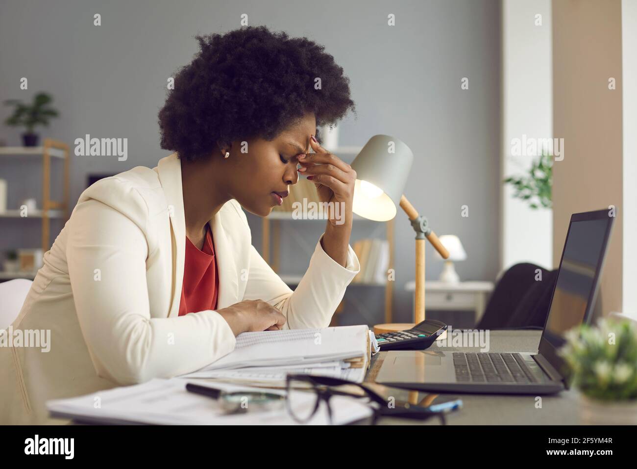 Frustrierte afroamerikanische Frau, die die Augen geschlossen hält und die Nase massiert Stockfoto