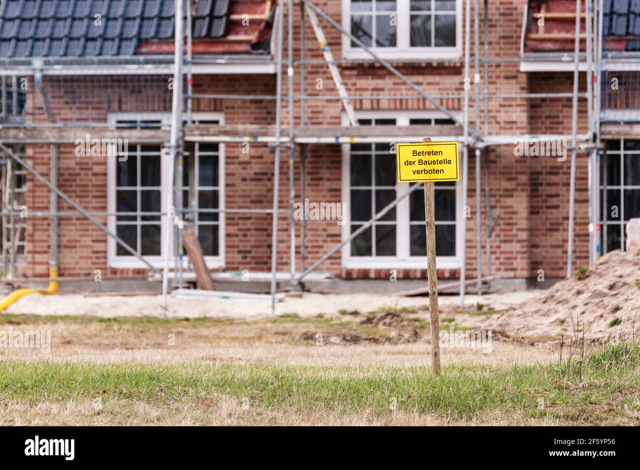 Vor einem fast fertigen Familienhaus befindet sich ein schild mit der deutschen Aufschrift Baustelle kein Zutritt Stockfoto