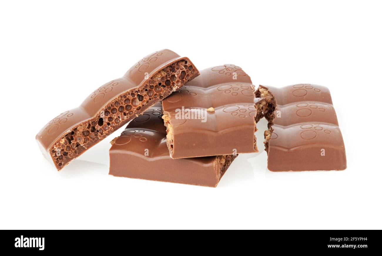 Stücke von köstlicher poröser Milchschokolade auf weißem Hintergrund Stockfoto