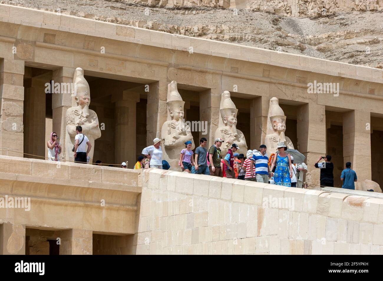 Touristen nähern sich den Osiris-Säulen auf der oberen Terrasse am Totentempel der Hatschepsut bei Deir al-Bahri in der Nähe von Luxor in Ägypten. Stockfoto