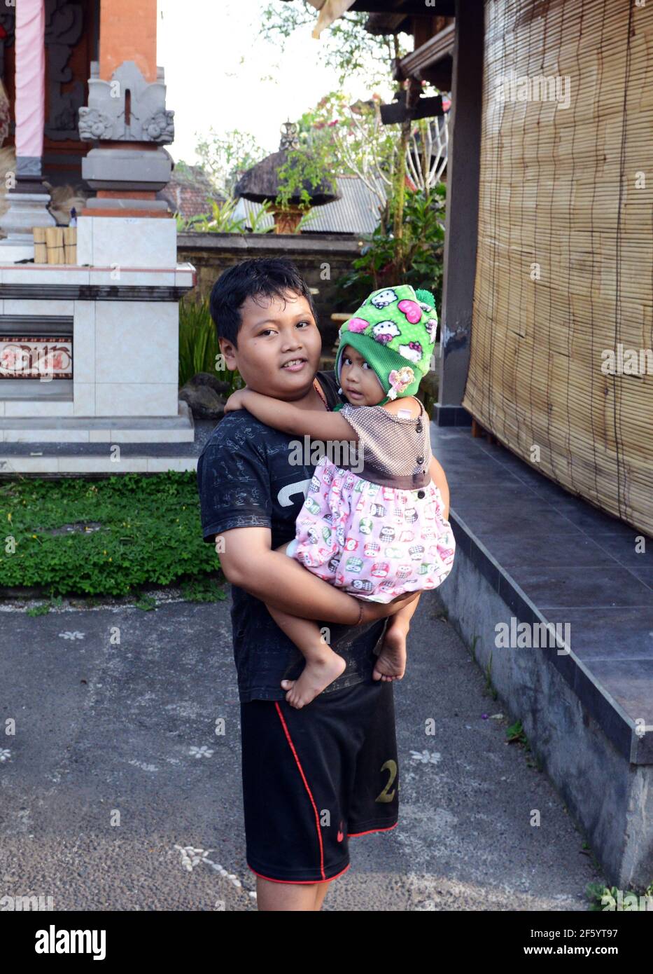 Ein süßer balinesischer Junge, der seinen Bruder in der Hand hält. Stockfoto