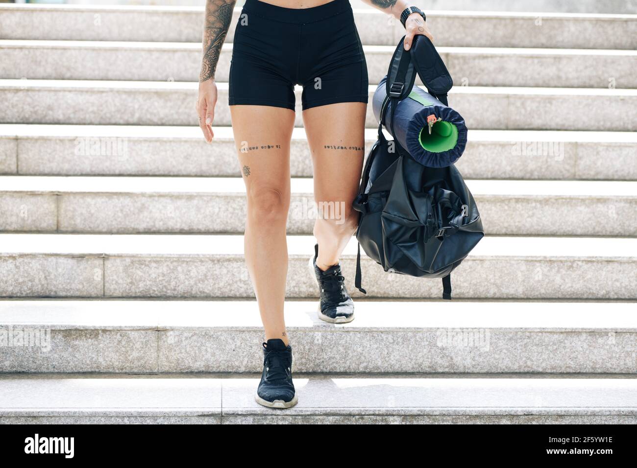 Beschnittenes Bild von fit junge Frau in Turnhalle Shorts zu Fuß Die Treppe runter mit Sporttasche in den Händen Stockfoto