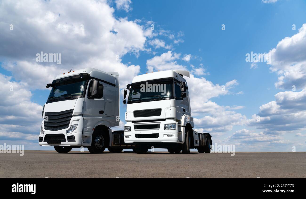 Zwei weiße Lastwagen gegen den blauen Himmel Stockfoto