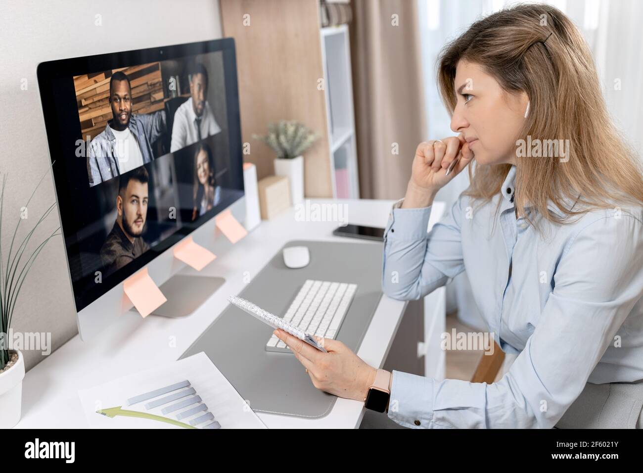 Konzentrierte schöne Geschäftsfrau nutzt Computer, mit einem Video-Meeting. Elegante, stilvolle Frau sitzt am Schreibtisch und diskutiert mit Stockfoto