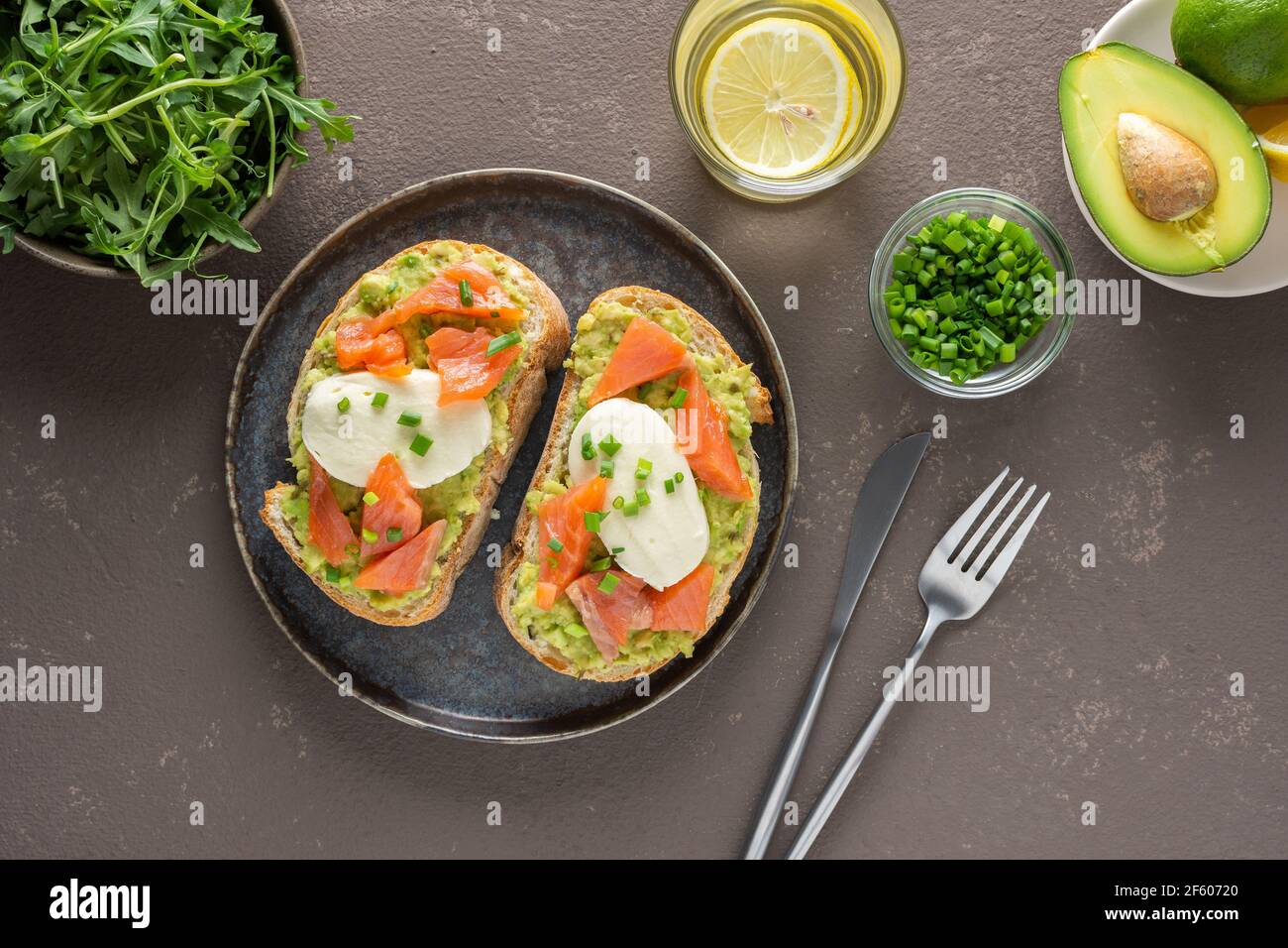 Leckeres herzhaftes Frühstück, Sandwiches mit Avocado-Paste, Lachs und Mozzarella auf einem Teller, Rucola und Erbsensprossen und grüne Zwiebel Stockfoto