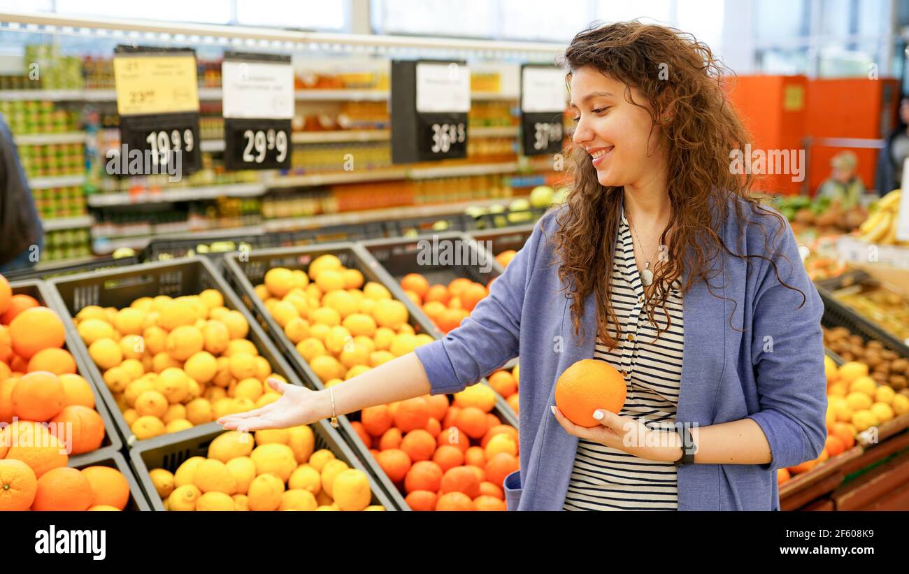Frau wählt Obst und Gemüse auf Bauernmarkt und hält Orange. Keine Verschwendung. Nachhaltiger Lebensstil. Stockfoto