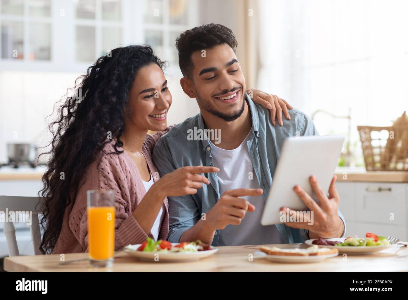 Fröhliche Naher Osten Ehegatten Mit Digital Tablet Beim Frühstück In Der Küche Stockfoto
