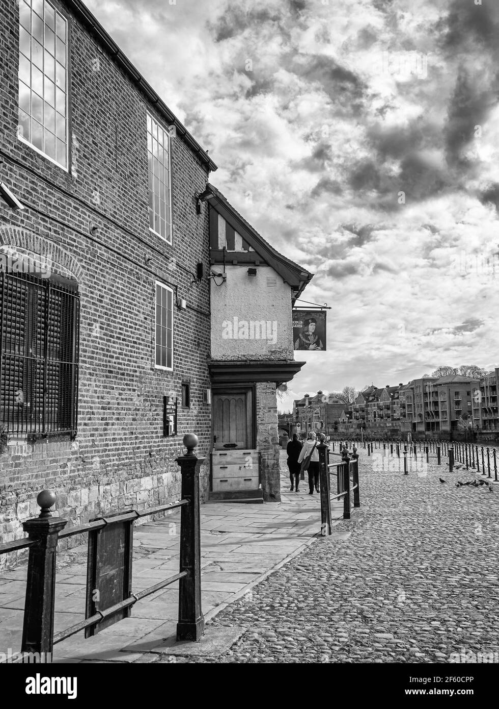 Riverside Pub in York. Das alte Gebäude liegt neben einem gepflasterten Pfad und einige Leute gehen vorbei. Wolkiger Himmel ist oben. Stockfoto