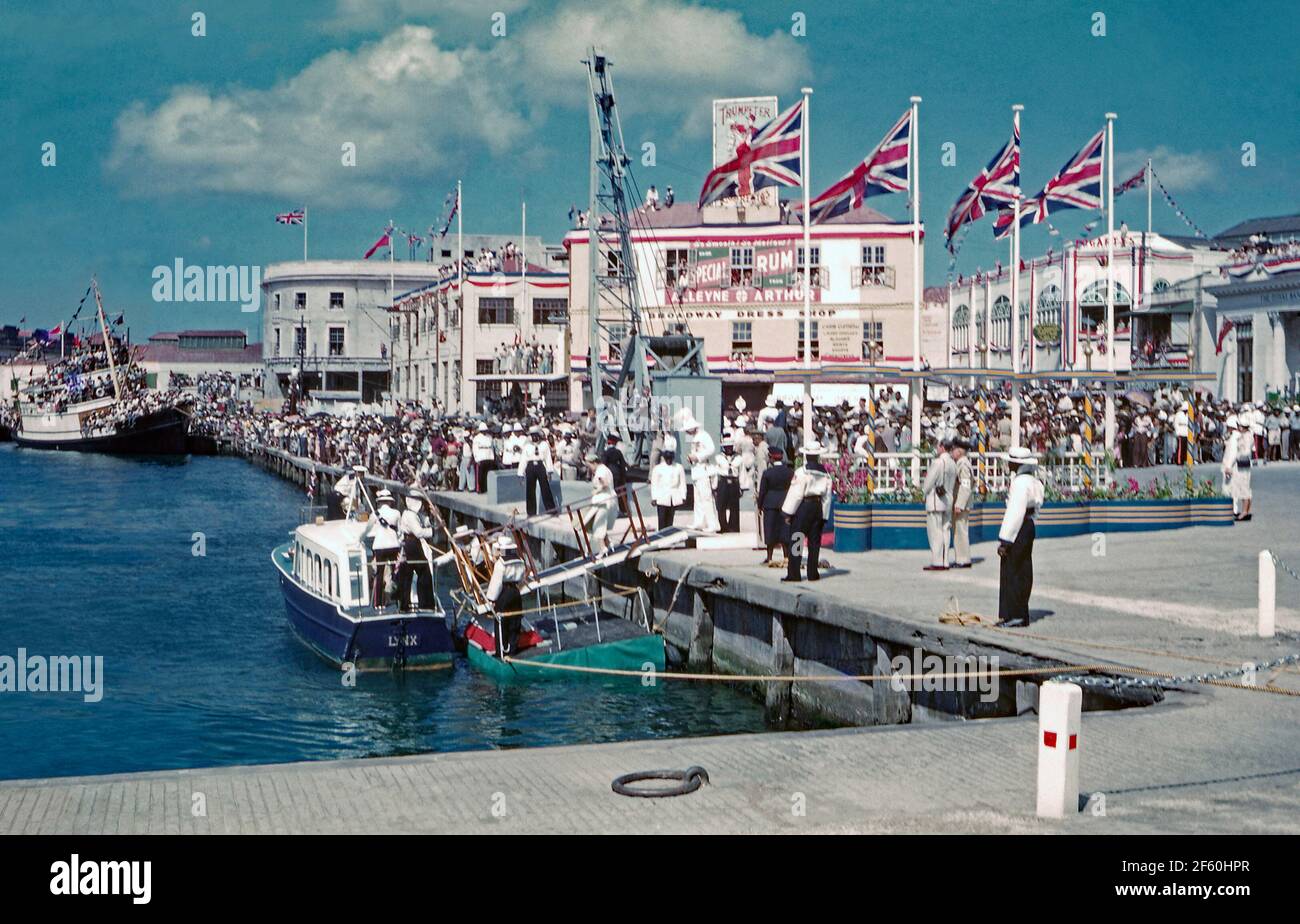 Crowd Scenes in Bridgetown, Barbados, 1955, während der Karibik-Tour von Prinzessin Margaret. Hier säumen Menschenmassen den Hafen am Trafalgar Square (heute National Heroes Square genannt). Würdenträger steigen an Bord der Tender, ‘Lynx’, um zur festgetäuten Royal Yacht ‘Britannia’ hinausgefahren zu werden. Im Januar 1955 machte die Prinzessin die erste von vielen Reisen in die Karibik, ihre Tour an Bord von Britannia zu den britischen Kolonien war in ganz Westindien beliebt. Prinzessin Margaret (1930 – 2002) war die Schwester von Königin Elisabeth II. Dieses Bild stammt von einem alten Amateur-35-mm-Farbtransparenz – einem Vintage-Foto aus den 1950er Jahren Stockfoto