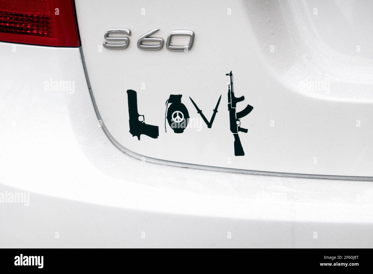 Ein gemischter Aufkleber auf der Rückseite eines geparkten Autos - Liebe, Frieden, Waffen, Granaten und Sturmgewehre. In Flushing, Queens, New York City. Stockfoto