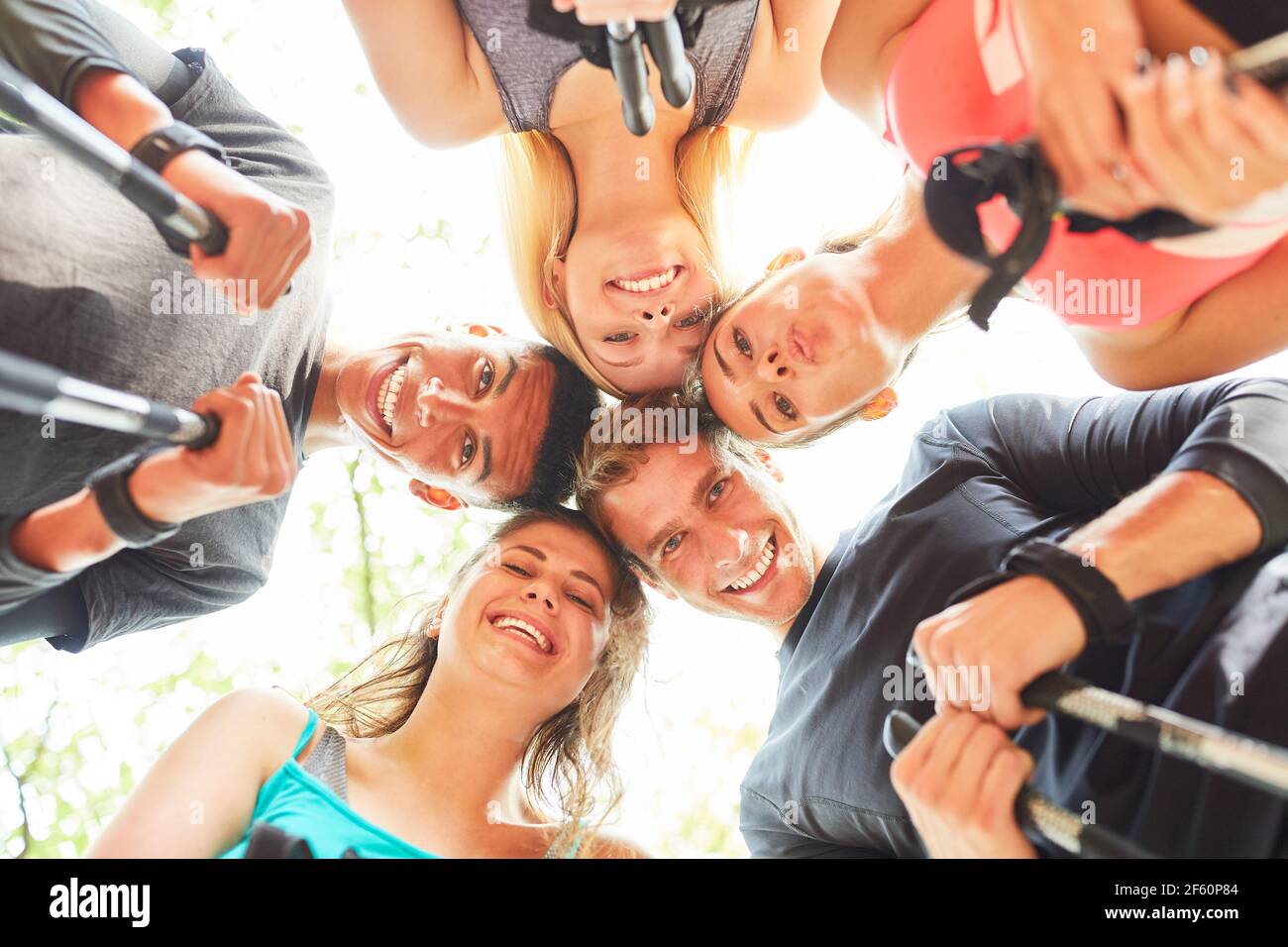 Gruppe von Teenagern als glückliche Freunde in einem Kreis während Nordic Walking Stockfoto