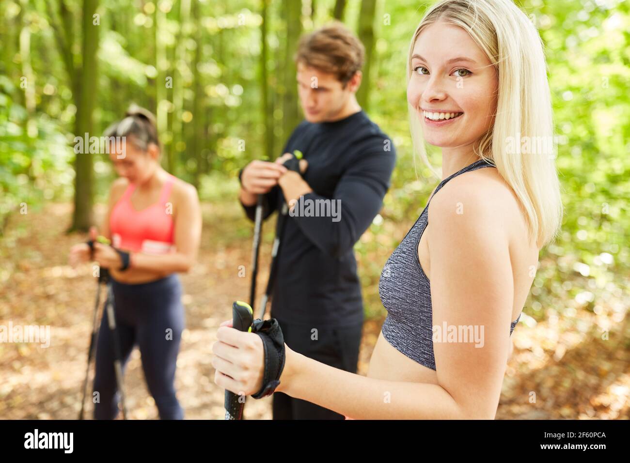 Aktive junge Frau, die zusammen mit Freunden Nordic Walking Sport macht In der Natur Stockfoto