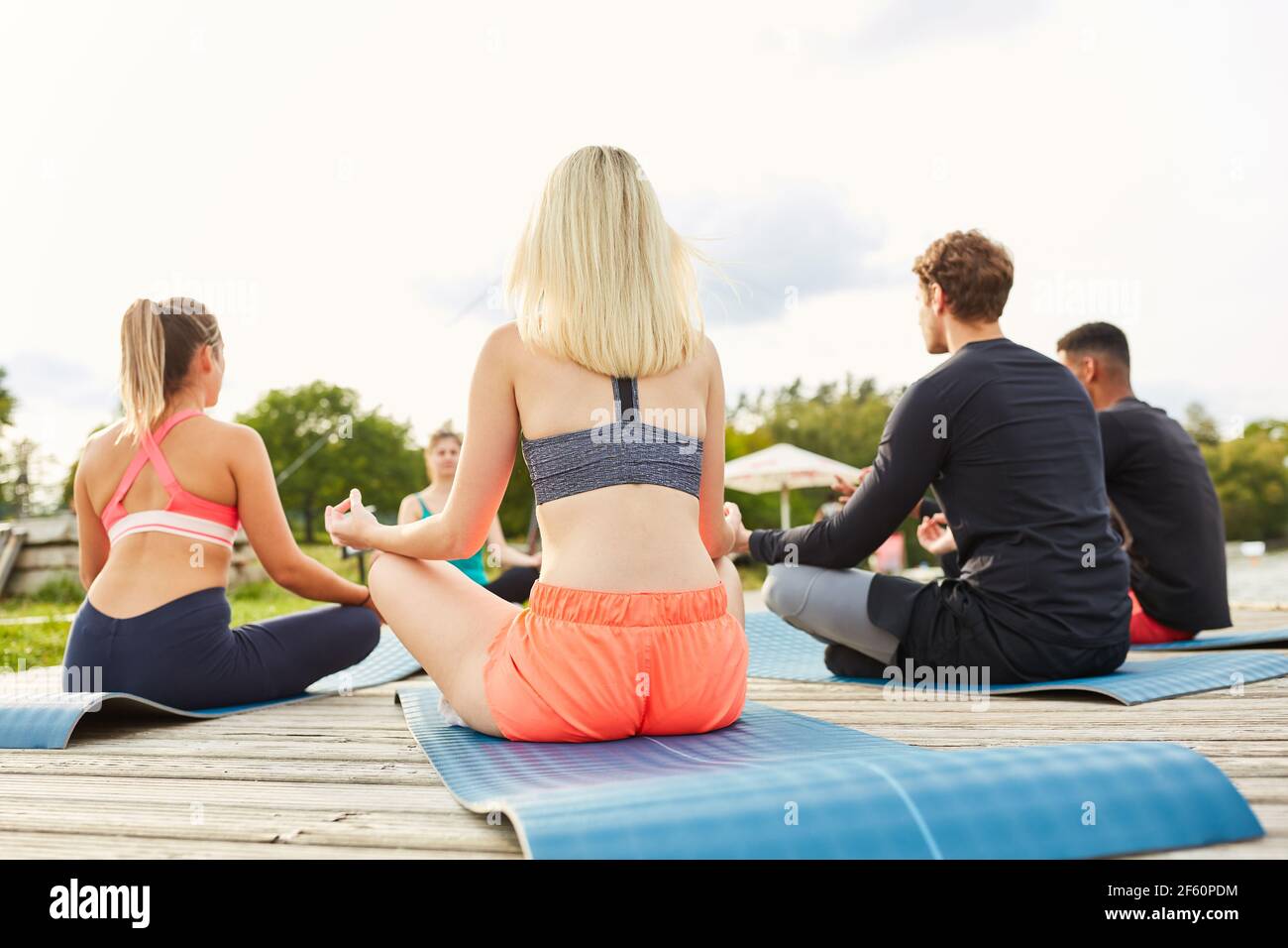 Junge Menschen sitzen im Kreis und meditieren In der Yoga-Outdoor-Werkstatt Stockfoto
