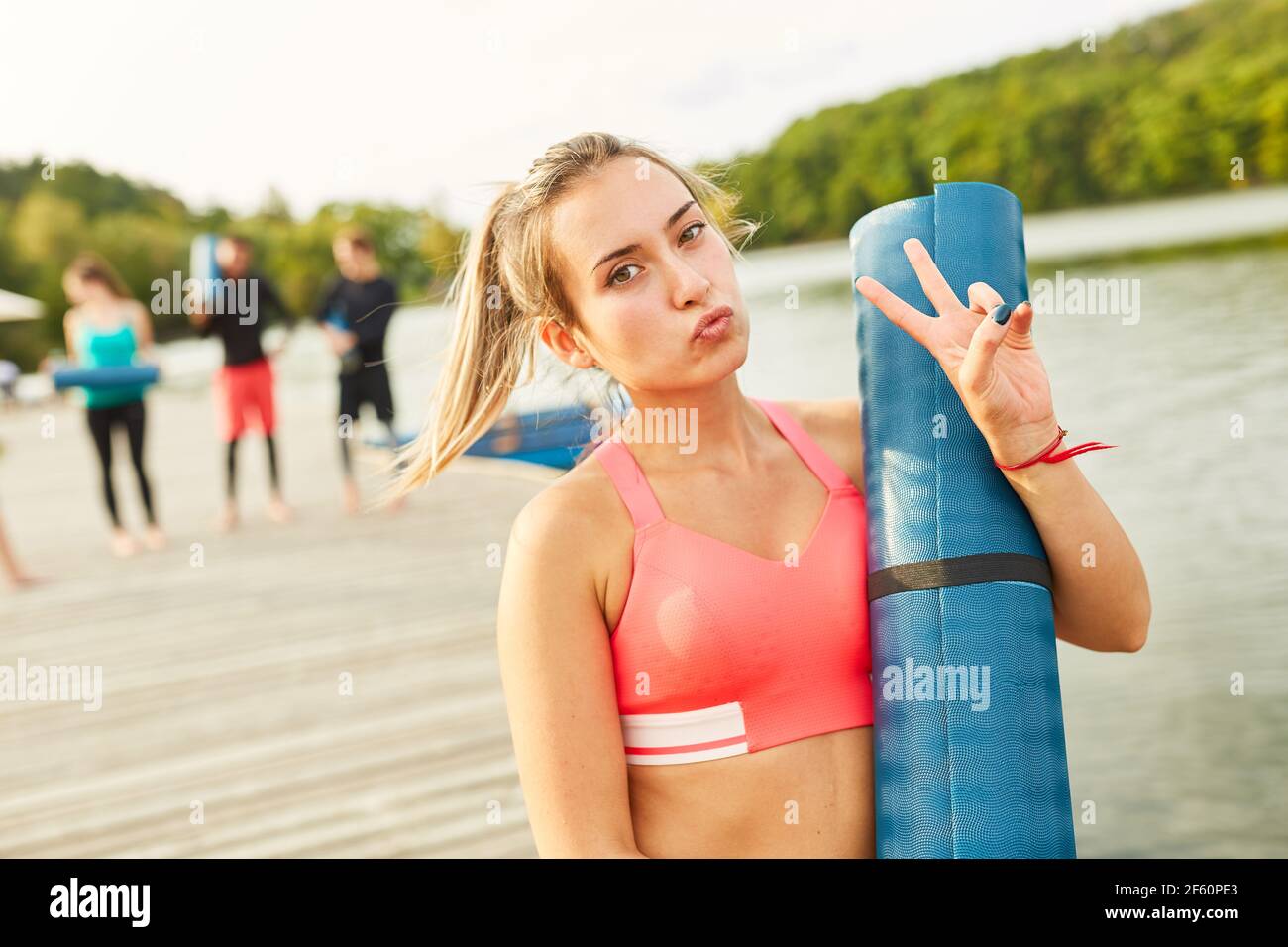 Sportliche und lässige junge Frau mit Yogamatte nach der Fitness Klasse am Seeufer Stockfoto