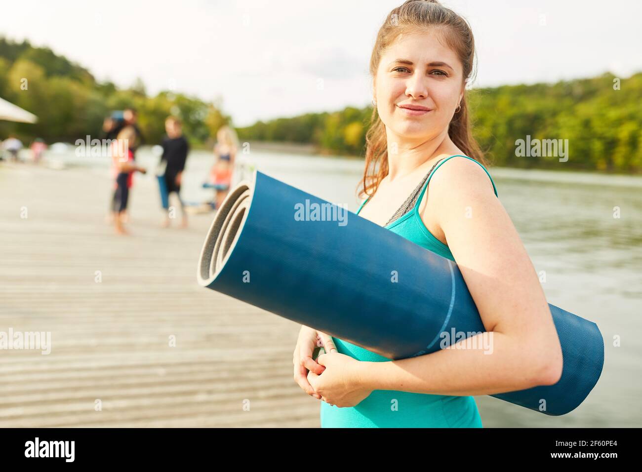 Junge Frau mit Yogamatte nach Yoga-Kurs auf Wellness Urlaub am See Stockfoto