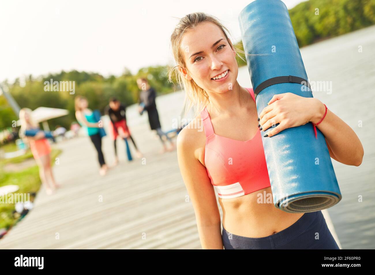 Junge Frau als Yogalehrerin mit Yogamatte nach Der Wellness-Kurs am Seeufer Stockfoto