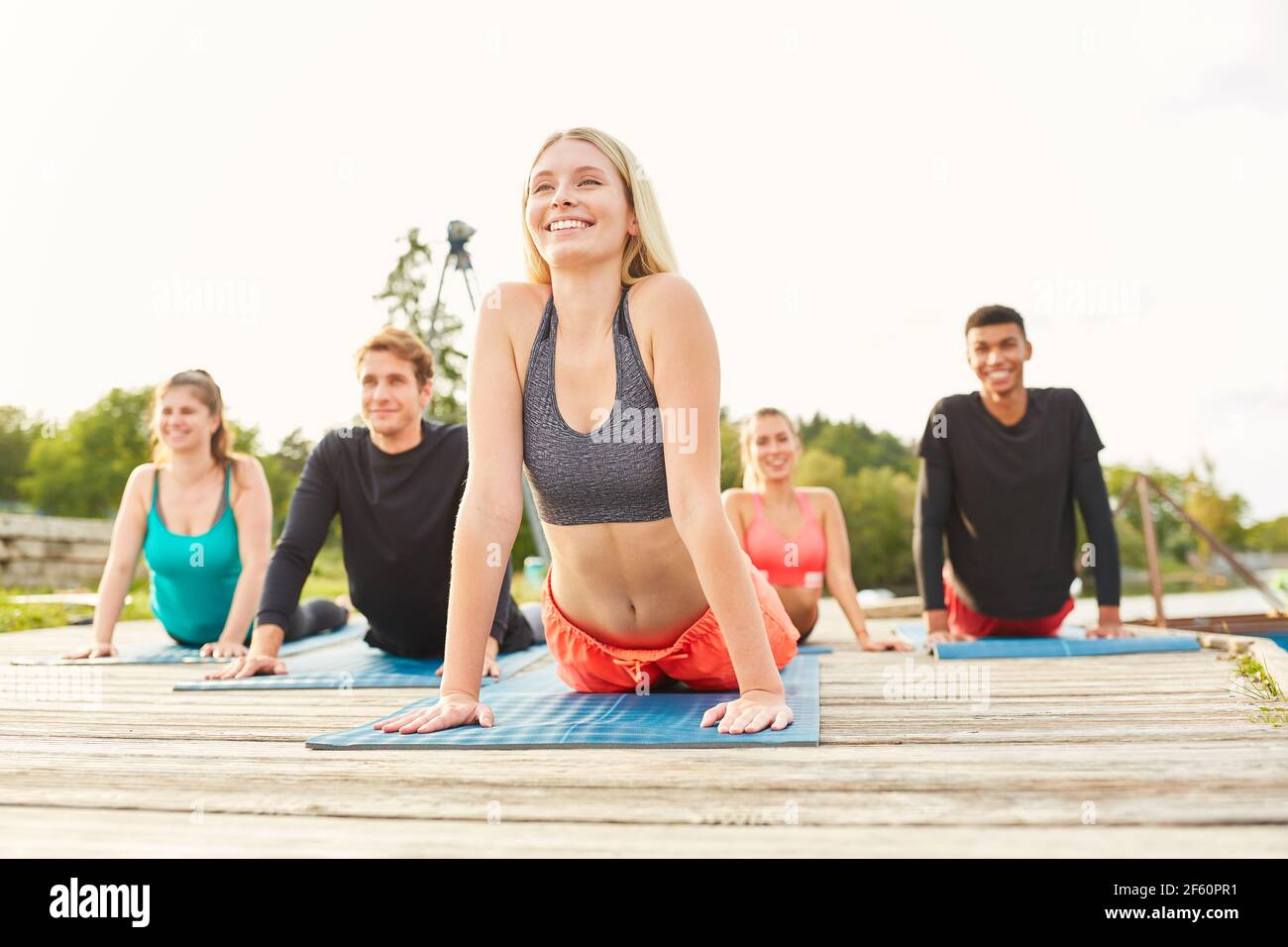 Junge Menschen machen Stretching-Übung in Yoga-Workshop in der Natur Am Seeufer Stockfoto