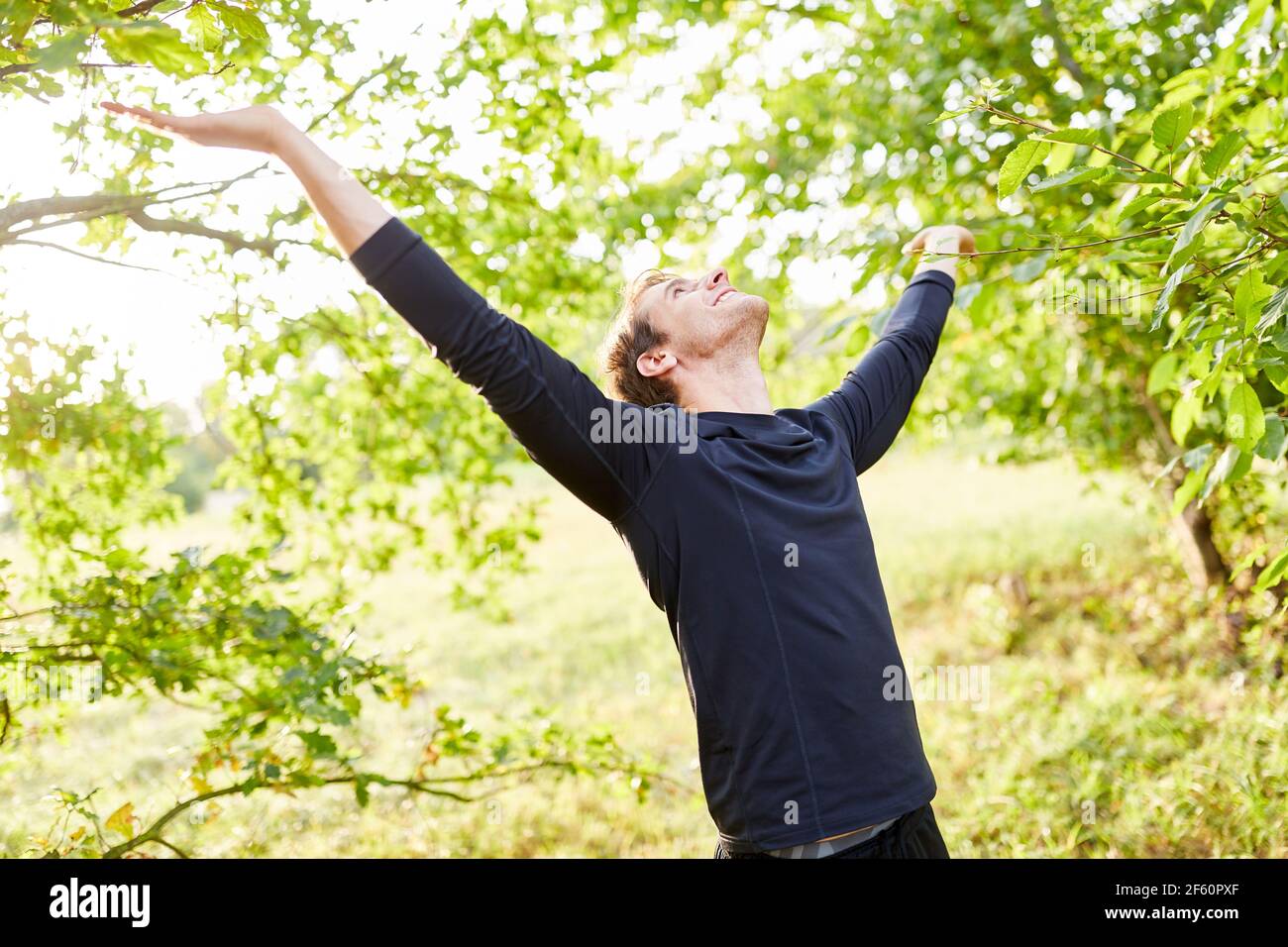 Glücklicher junger Mann atmet Luft in der freien Natur in Sommer Stockfoto
