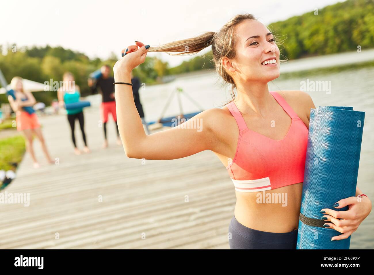Attraktive und sportliche junge Frau mit Yogamatte nach einem Fitnesskurs Stockfoto