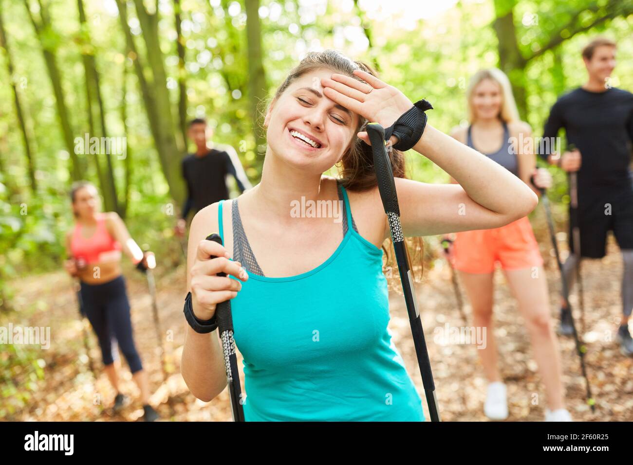 Erschöpfte junge Frau auf Nordic Walking Kurs mit Freunden in Natur im Sommer Stockfoto