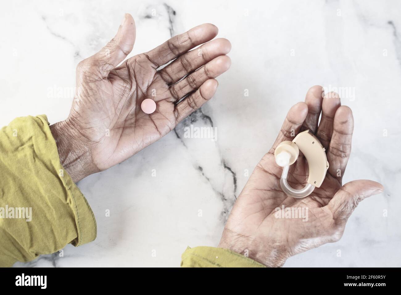 Hörgeräte und Pillen auf der Handfläche halten Stockfoto