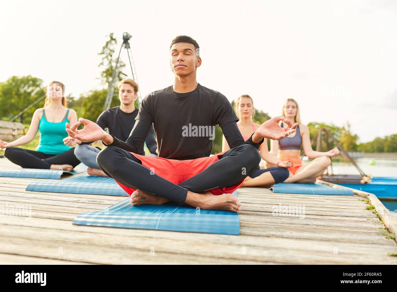 Gruppe von Freunden in der Lotusposition genießen ein Zen Meditation in einem Seeufer Yoga-Kurs Stockfoto