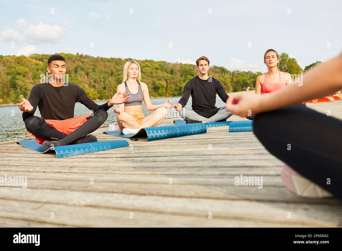 Jugendliche machen Yoga in einem Wellness-Workshop auf dem Seeufer im Sommer Stockfoto
