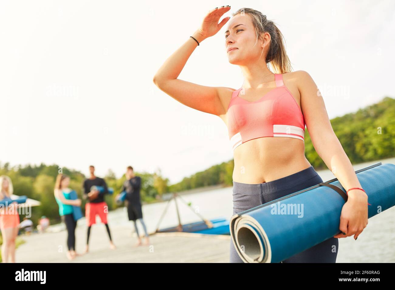 Junge Frau auf Wellnessurlaub mit Yogamatte in der Natur Im Sommer am See Stockfoto