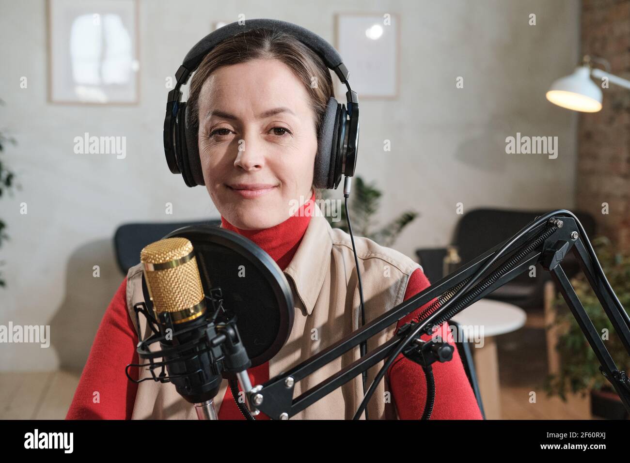 Porträt einer jungen Frau in Kopfhörer sprechen im Mikrofon während Rundfunk sie arbeitet im Radio Stockfoto