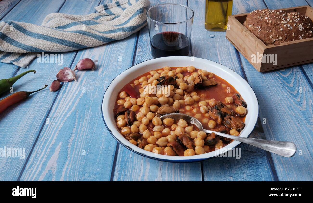 Rezept für Muscheln mit Kichererbsen, Glas Rotwein und Brot, typisch spanisches Gericht, fertig zum Essen Stockfoto