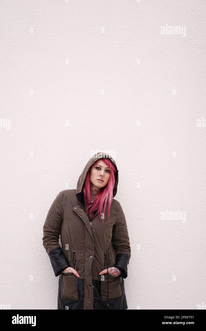 Junge Frau mit rosa Haardurchstechungen und Tattoos an der Wand Mit Kopierbereich Stockfoto