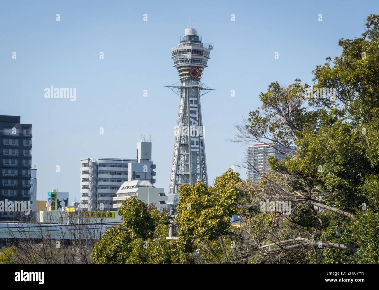 Blick auf den berühmten Tsutenkaku Tower, in Shinsekai, Osaka, Japan. Aufgenommen vom Tennoji Park, der an einem sonnigen Tag durch die Bäume schaut Stockfoto