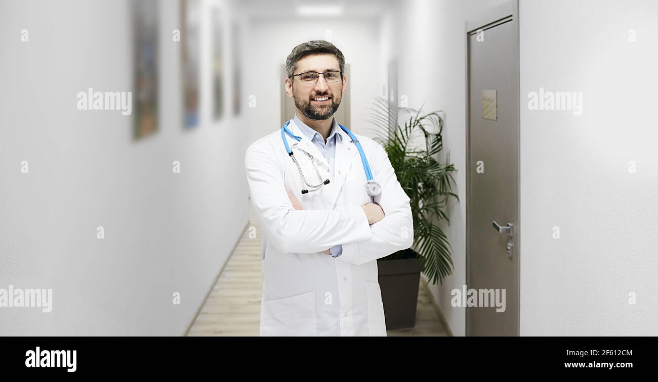 Portrait eines gut aussehenden reifen Hausarztes mit Phonendoskop in der Moderne Klinikkorridor Stockfoto
