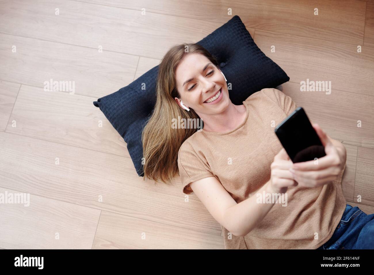 Fröhliche junge Frau auf dem Boden ruhen und Videoaufnahmen Freund oder Freund, Blick von oben Stockfoto