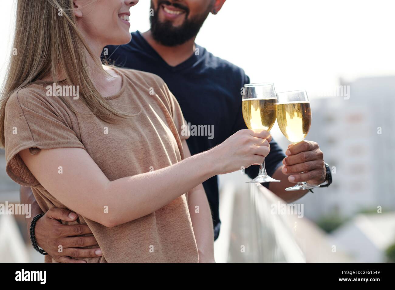 Zugeschnittenes Bild von lächelndem umarmenden jungen Paar genießen Champagner trinken Auf dem Dach Stockfoto