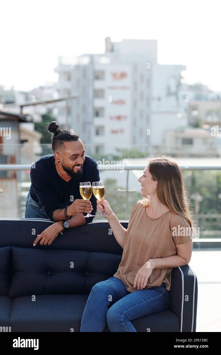 Lächelnder junger Mann und Frau trinken Champagner und flirten an Dachdeckerparty Stockfoto