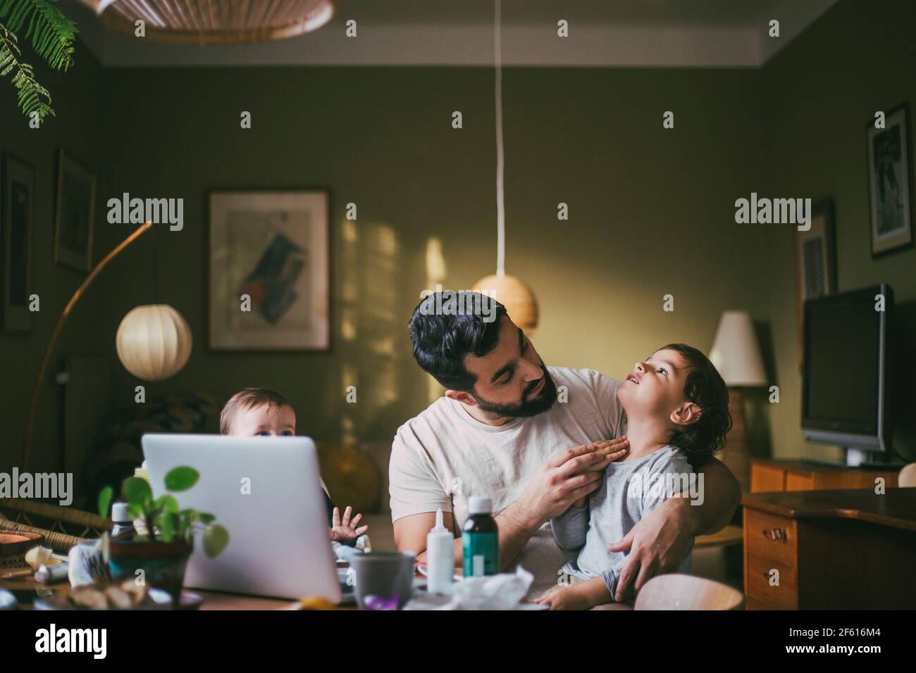 Vater mit Kindern, die Ratschläge zu Videoanrufen über Laptop Zu Hause während der COVID-19 Stockfoto