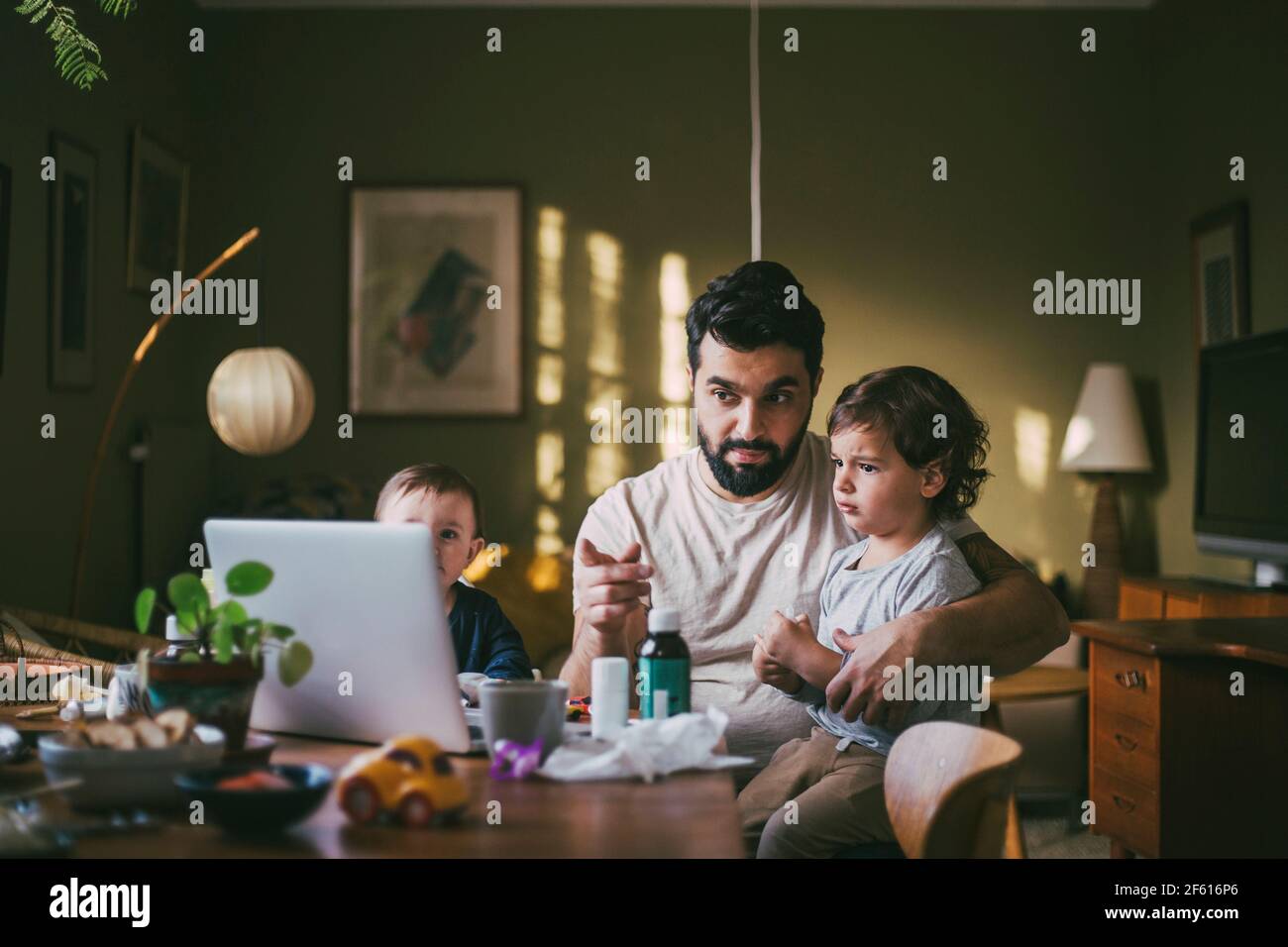 Vater mit Kindern, die Ratschläge zu Videoanrufen über Laptop Zu Hause während einer Pandemie Stockfoto